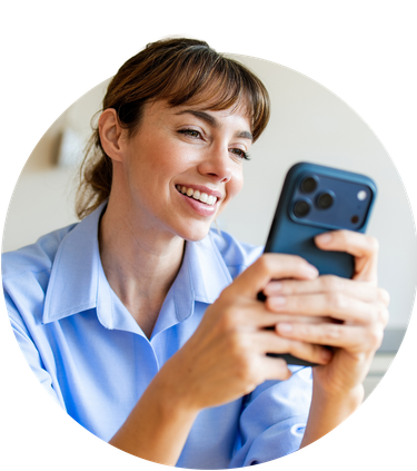 A confident, smiling young woman looking off to the side with her phone in both hands.